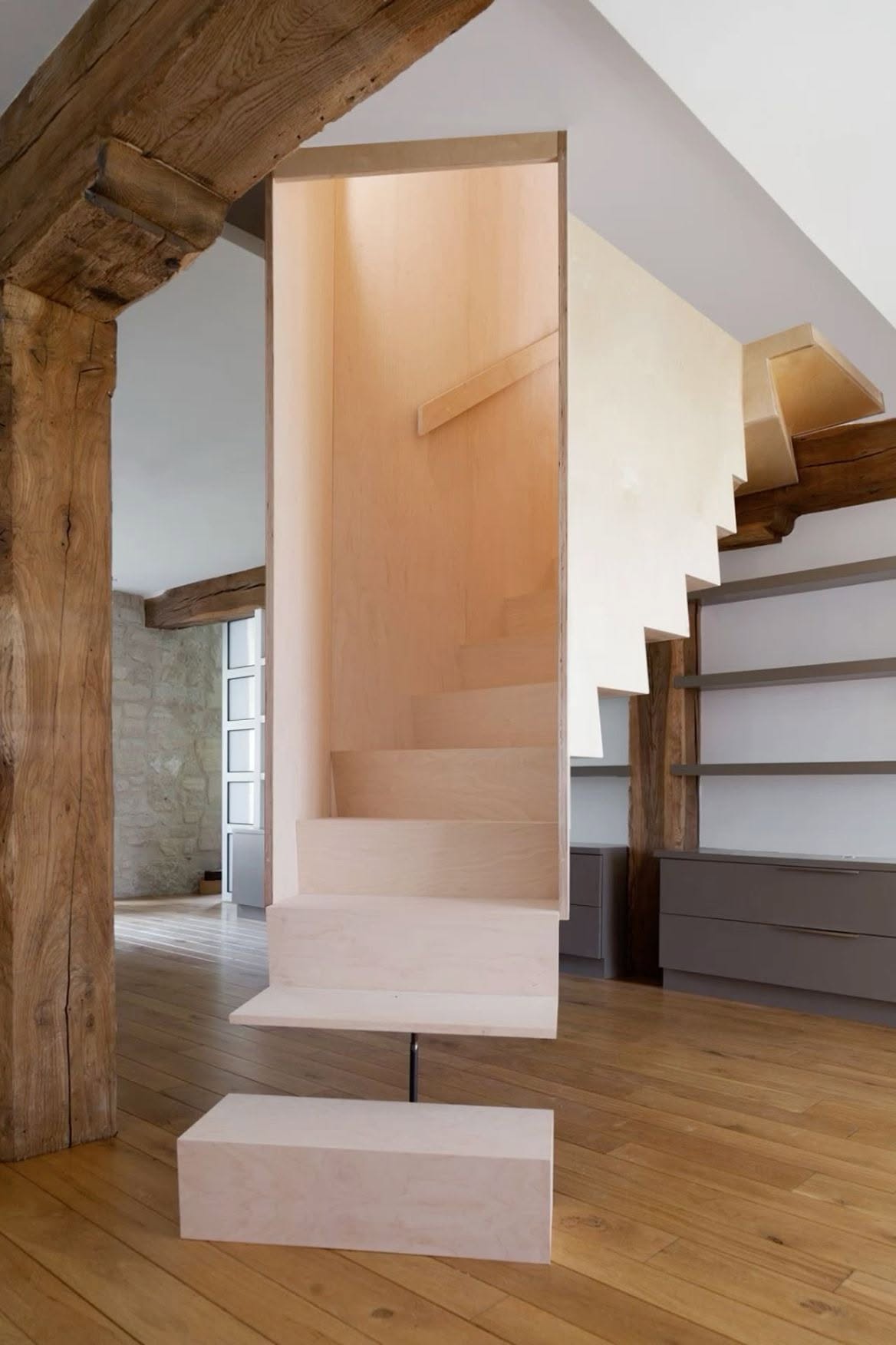 Escalera suspendida de madera clara entre vigas antiguas de roble