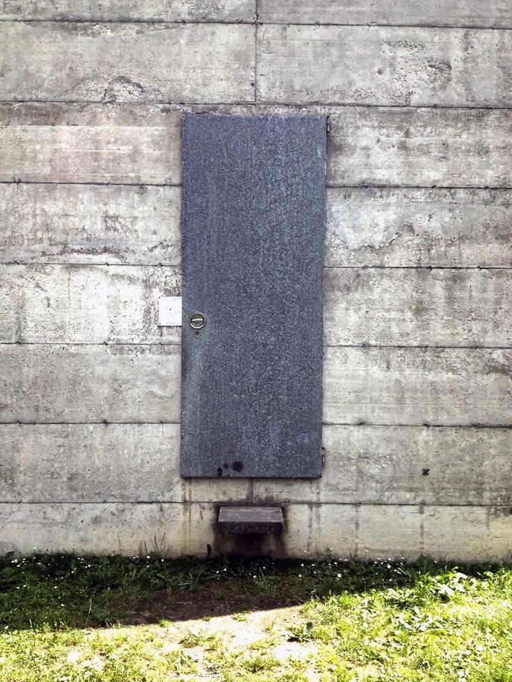 Puerta metálica cerrada sobre el muro de hormigón del Museo La Congiunta