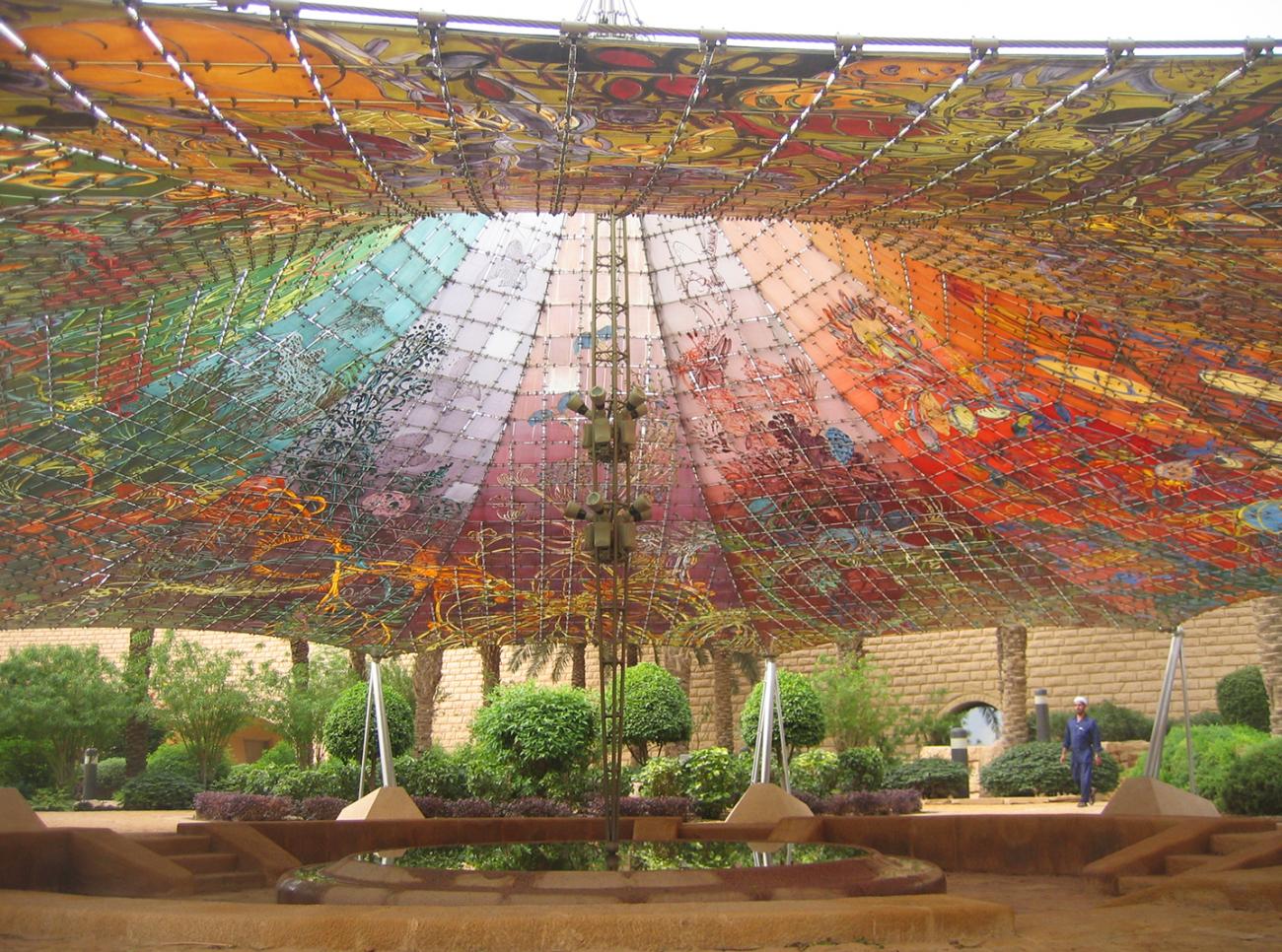 Carpa tensada de vivos colores sobre un jardín en Arabia