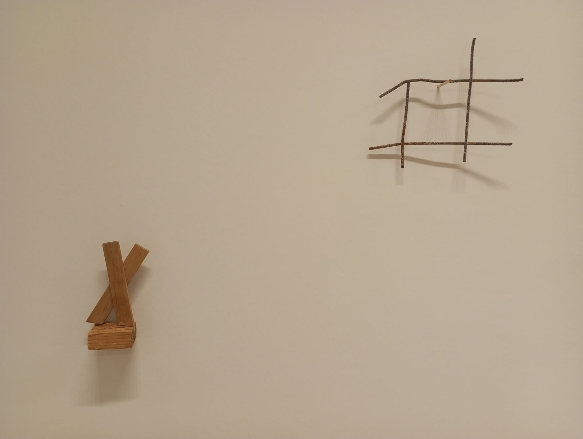 Dos piezas en la pared: listones de madera cruzados y una retícula de hierro oxidado