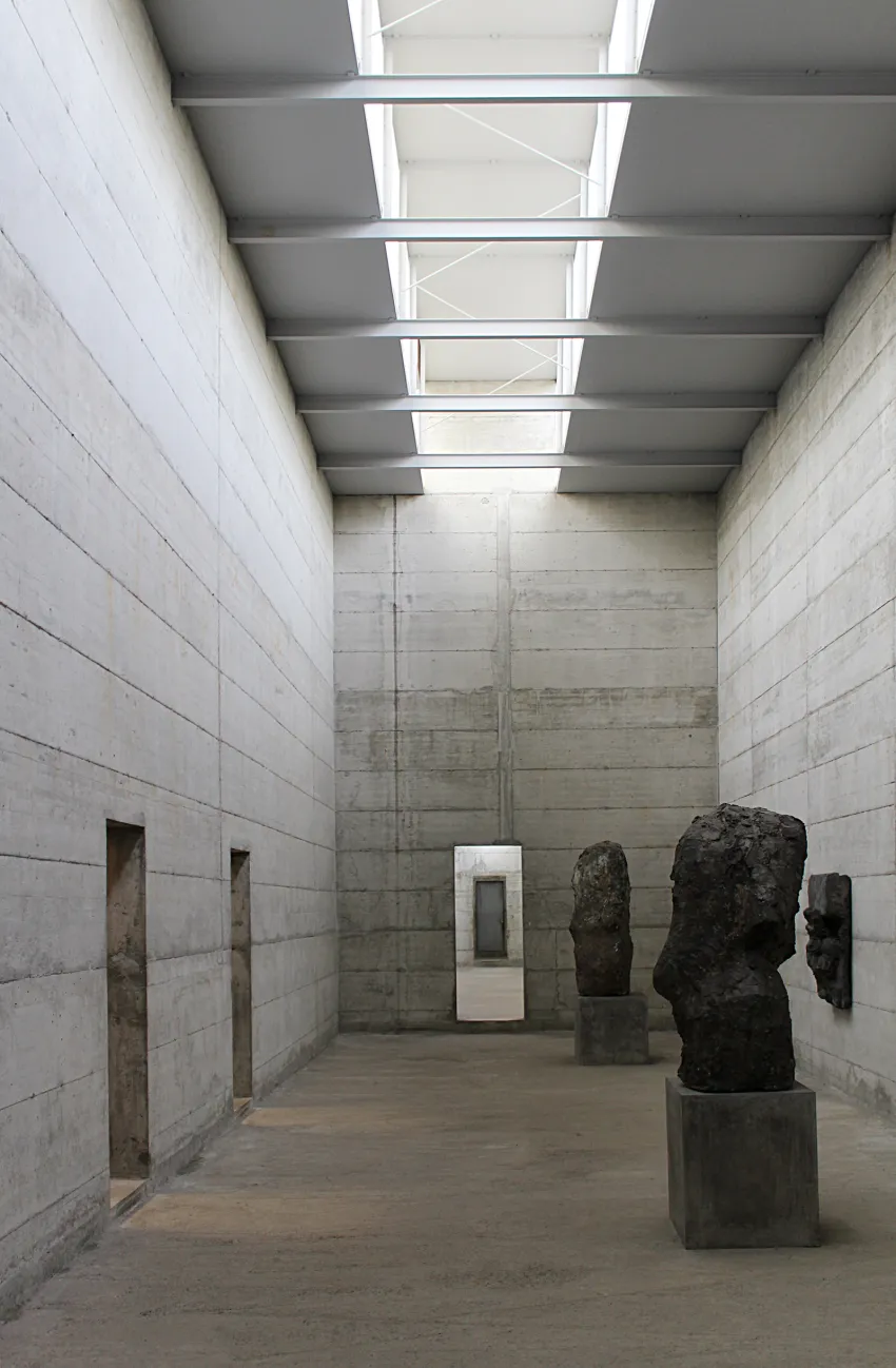 Sala alta de hormigón del Museo La Congiunta iluminada por lucernarios, con esculturas de Hans Josephsohn