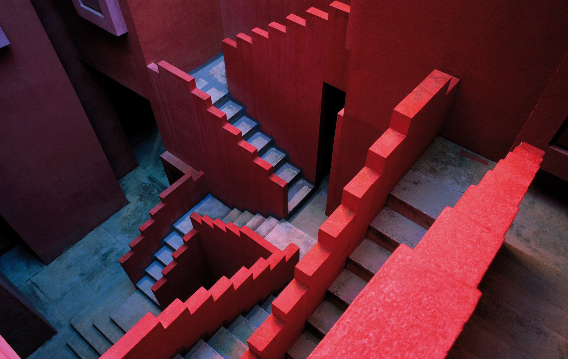 Escaleras rojas y azules entrecruzadas en un patio de La Muralla Roja