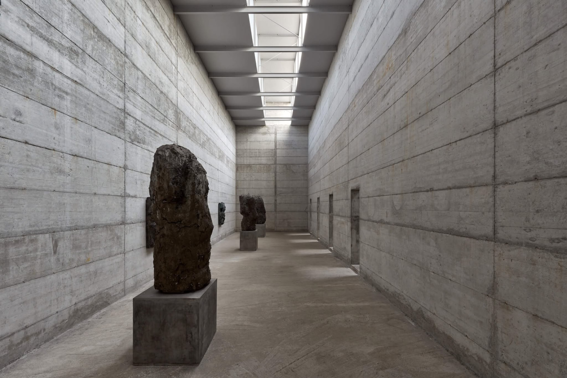 Galería longitudinal de hormigón con esculturas de Hans Josephsohn bajo luz cenital