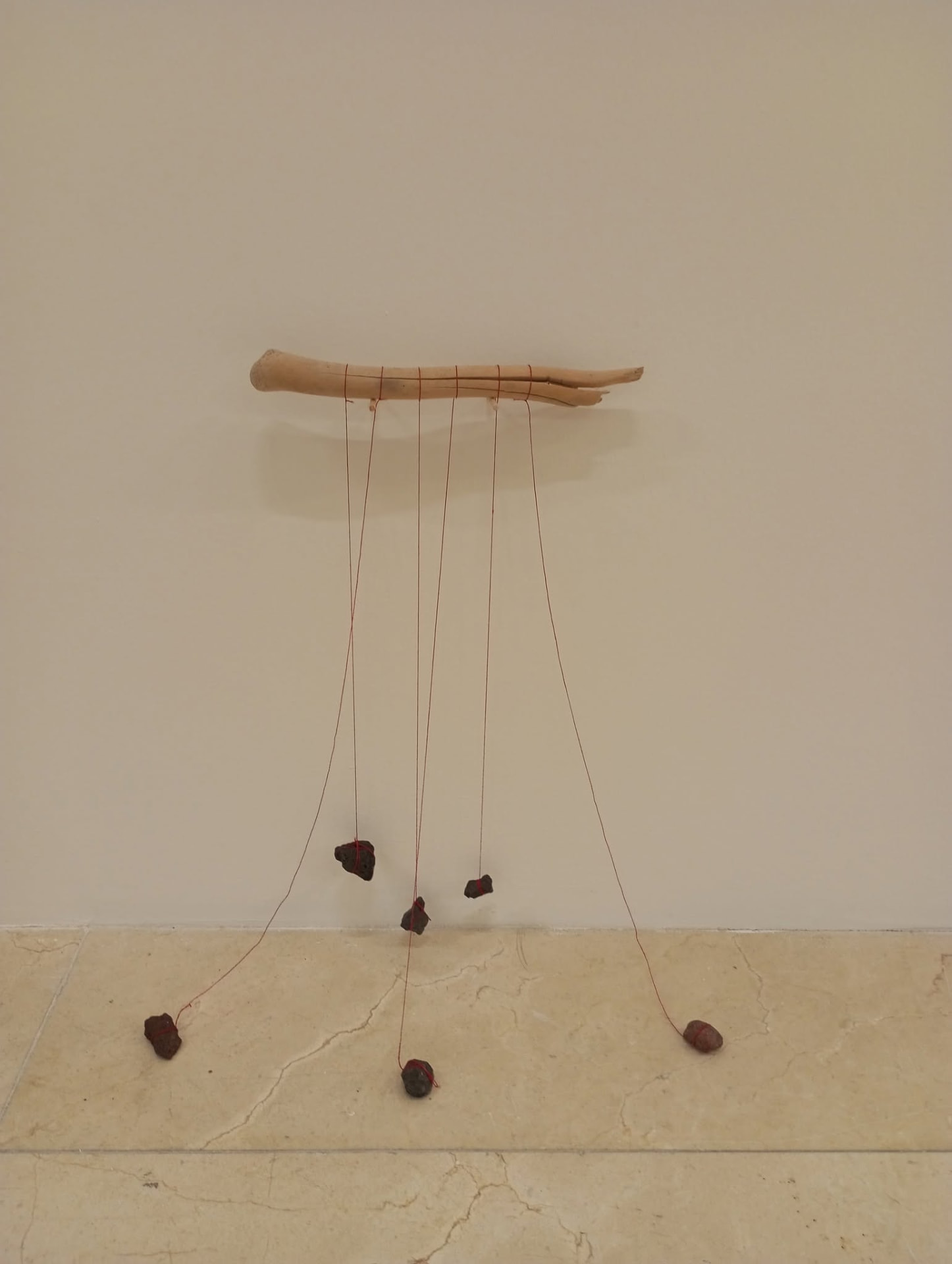 Un tronco de madera a la deriva del que cuelgan piedras atadas con hilos rojos