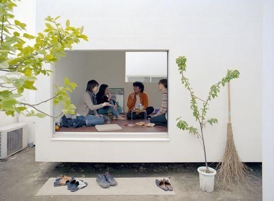 Ventana de la Casa Moriyama con personas sentadas en el piso, mirando al patio