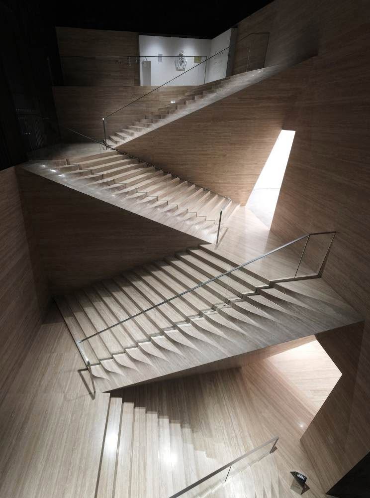 Tramos de escalera de mármol superpuestos atravesados por una franja de luz