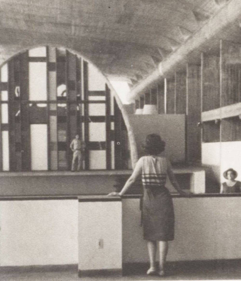 Foto histórica del interior, con una mujer apoyada en la baranda frente al arco vidriado